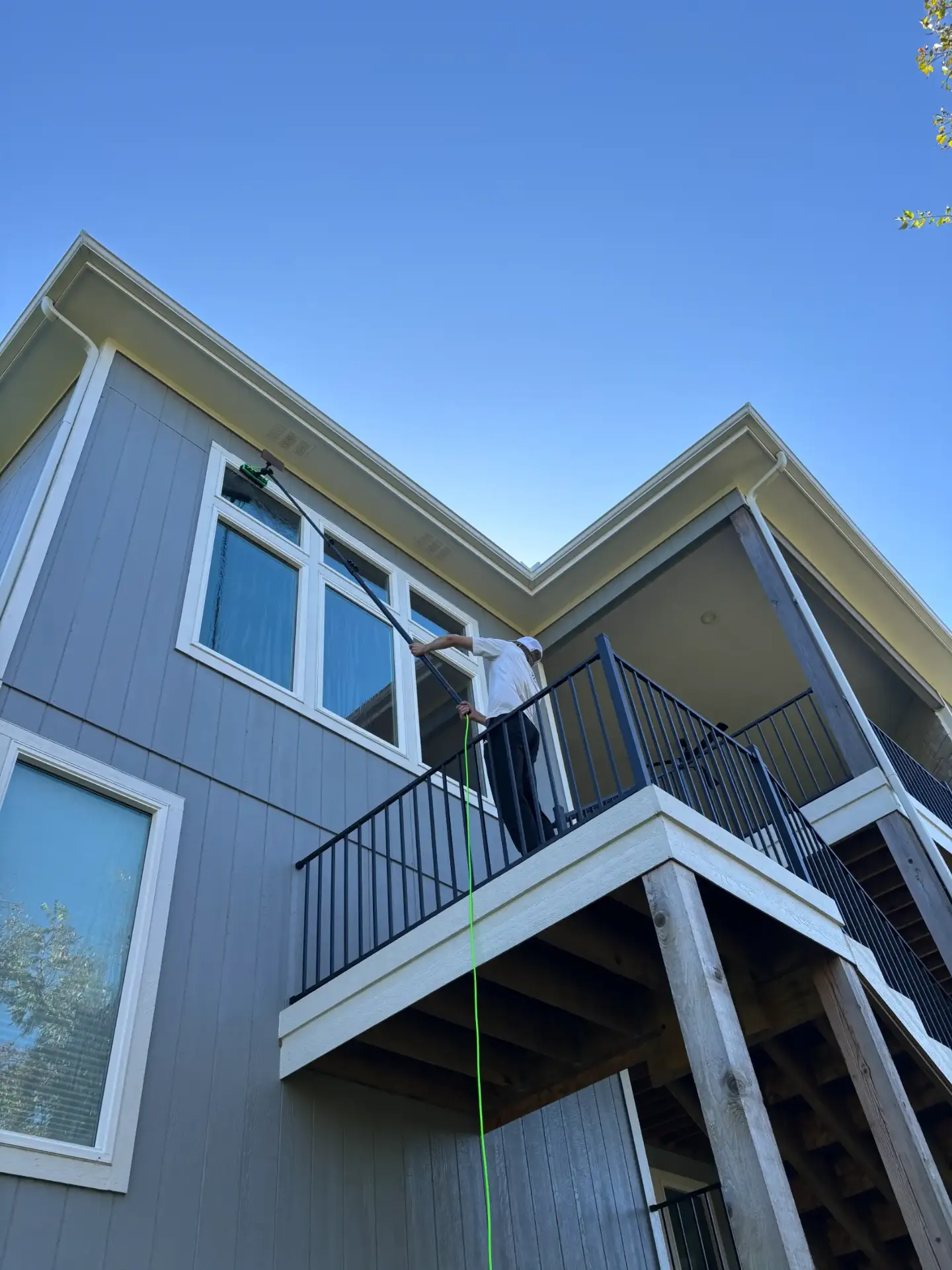 Technician cleaning exterior house windows with a squeegee